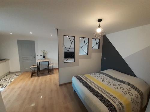 ein Schlafzimmer mit einem Bett und einen Flur mit einem Tisch in der Unterkunft Studio Le Ménascle in Saint-Georges-de-Luzençon