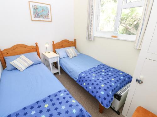 2 Einzelbetten in einem Zimmer mit 2 Fenstern in der Unterkunft Drake Cottage in Seaview