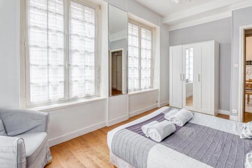 a white bedroom with a bed and windows at Ermine - Intramuros proche plage - St Malo in Saint Malo
