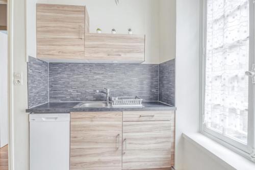 une petite cuisine avec un évier et une fenêtre dans l'établissement Ermine - Intramuros proche plage - St Malo, à Saint-Malo