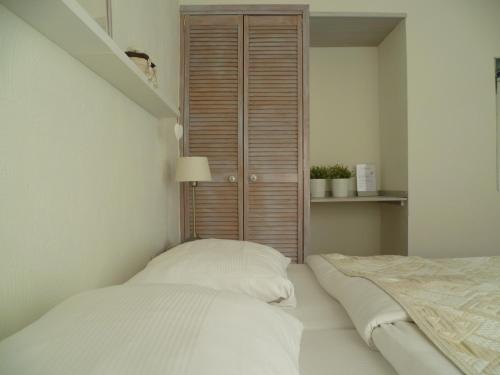 a white bedroom with a bed and a closet at Hotel Pension Oranje in Valkenburg