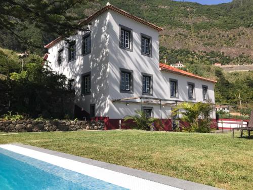 a white house with a swimming pool in front of it at Casa Oliveira Esmeraldo - Guest Houses in São Vicente