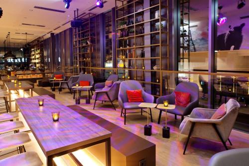 a restaurant with chairs and tables and a bar at Hotel Indigo Berlin - East Side Gallery in Berlin
