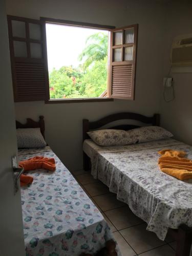 two beds in a room with a window at Apartamento Dom Ximenes in Porto De Galinhas