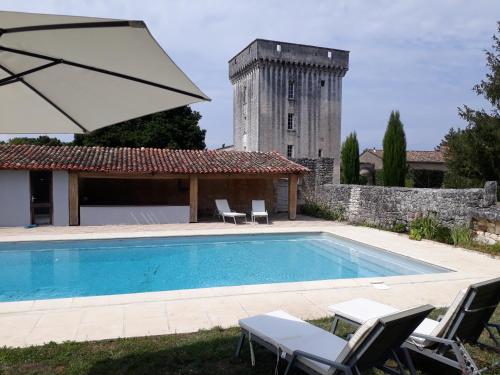 a swimming pool with chairs and an umbrella and a building at Château de la Tour du Breuil in Le Breuil