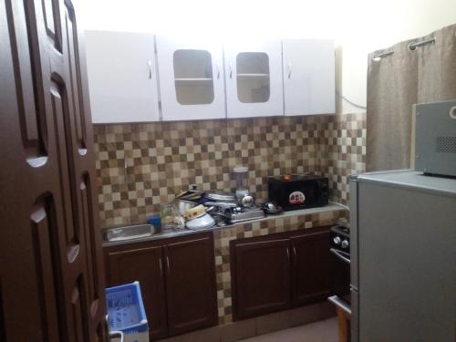 eine kleine Küche mit einem Herd und einem Kühlschrank in der Unterkunft Appartement ABS in Abidjan