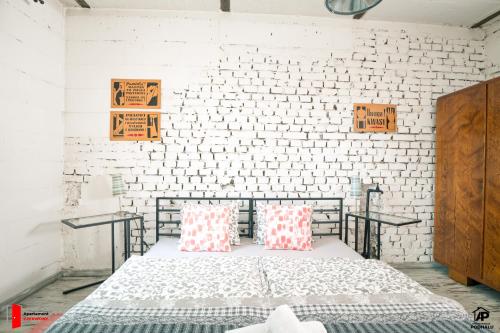 een slaapkamer met een bed en een witte bakstenen muur bij Apartamenty na Podhalu in Nowy Targ