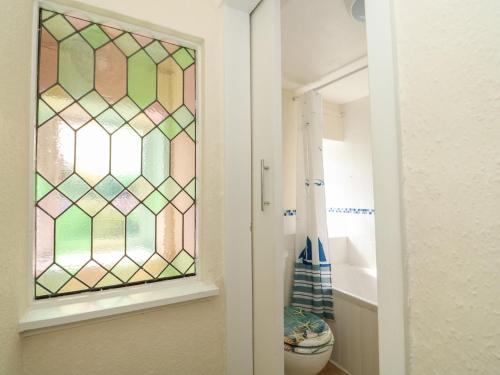 a bathroom with a stained glass window next to a toilet at Cobbler's Cottage in Norwich