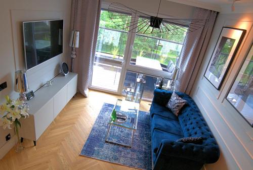 a living room with a blue couch and a tv at Blue Velvet Premium Apartments III in Toruń