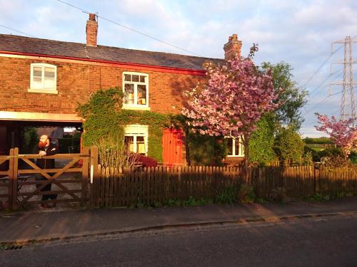 a woman standing outside of a house with a fence at The Old Post Office B&B in Lymm