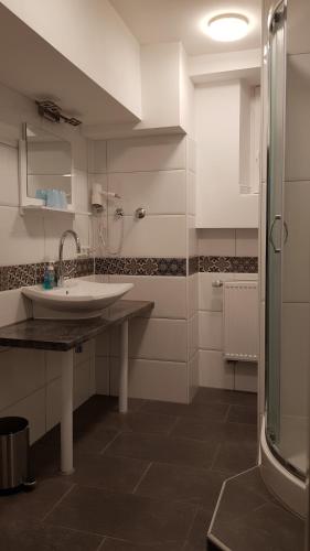biała łazienka z umywalką i prysznicem w obiekcie Hotel-Pension Adler Untertürkheim w Stuttgarcie