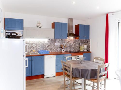 une cuisine avec des placards bleus et une table avec des chaises dans l'établissement maison au bord de la mer, à Plouhinec