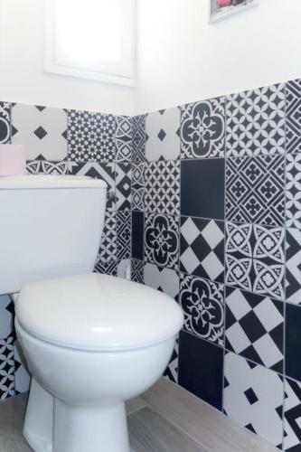 La salle de bains est pourvue de toilettes blanches et de carrelage. dans l'établissement maison au bord de la mer, à Plouhinec