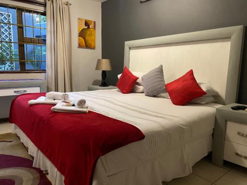 a bedroom with a large bed with red pillows at Marion Lodge in Johannesburg