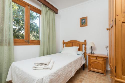 a bedroom with a bed with white sheets and a window at Villa YESERO in Pollença