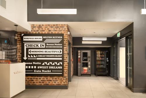 um lobby com uma parede de tijolos com placas em easyHotel Milton Keynes em Milton Keynes