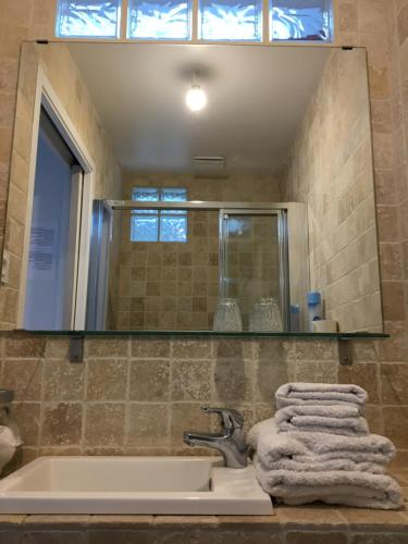 La salle de bains est pourvue d'un lavabo, d'un miroir et de serviettes. dans l'établissement Olive et Pomme, à Bretteville