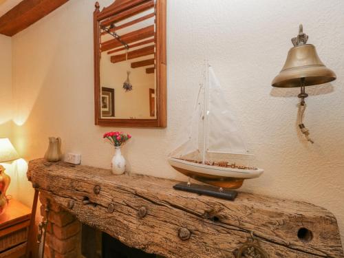 a model boat on top of a wooden table with a mirror at Shipwreck Cottage in Millom