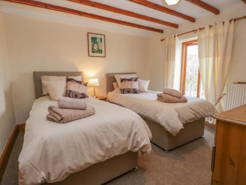 a bedroom with two beds and a window at Shipwreck Cottage in Millom