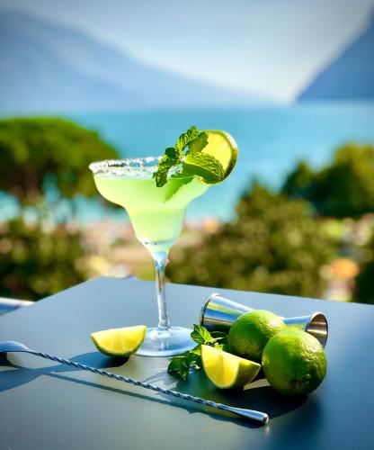 a margarita in a glass on a table with limes at Hotel Bellariva in Riva del Garda