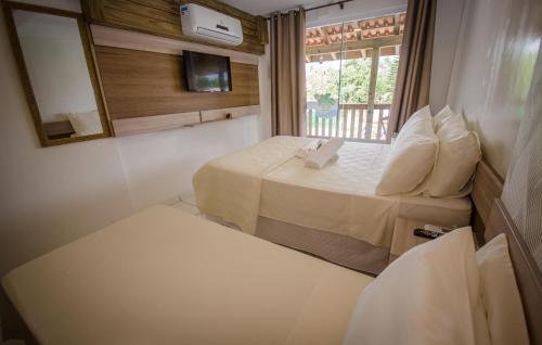 um pequeno quarto com 2 camas e uma janela em Hotel Costa Praia em Piçarras