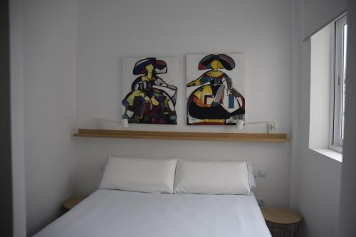 een bed in een kamer met twee foto's aan de muur bij Triana Parque VV in Las Palmas de Gran Canaria