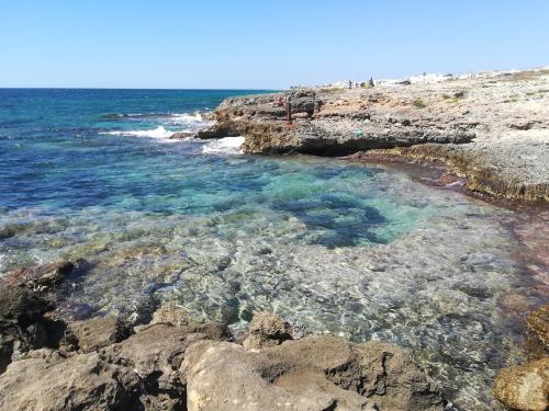 una spiaggia rocciosa con acqua blu e rocce di Casa vacanze Azure a Torre Suda