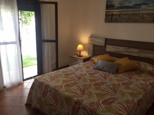 ein Schlafzimmer mit einem Bett mit einer Lampe und einem Fenster in der Unterkunft Casa Ananda y Casa Rengue in Conil de la Frontera