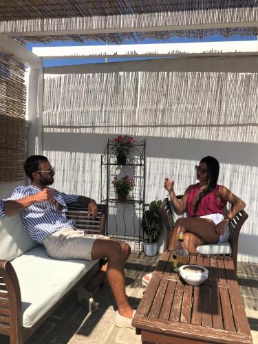 a man and woman sitting on a bench on a porch at Nenetta Rooms & Suites Monopoli in Monopoli