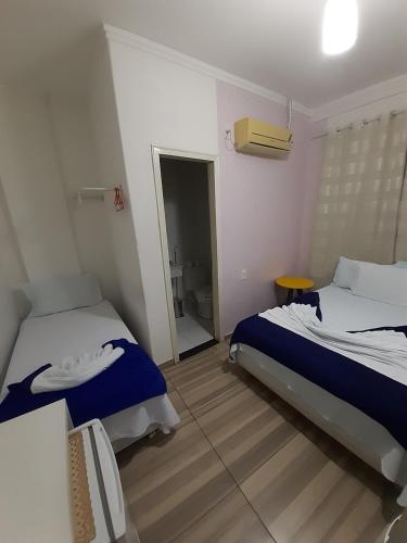 a hotel room with two beds and a bathroom at Pousada Rekinty in Canindé de São Francisco