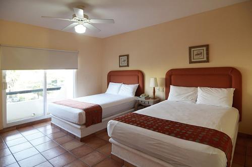 a hotel room with two beds and a window at Suites Las Palmas in San José del Cabo
