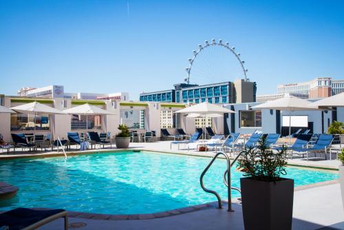 a swimming pool with chairs and a ferris wheel in the background at The Platinum Hotel in Las Vegas