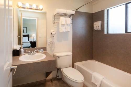 a bathroom with a toilet and a sink and a tub at The Grove West Seattle Inn in Seattle