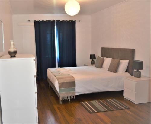 ヴィーラ・フランカ・ド・カンポにあるApartamento de Vila Franca do Campoのベッドルーム1室(青いカーテン付きの大型ベッド1台付)
