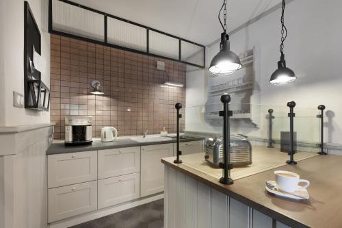 a kitchen with white cabinets and a counter with a coffee maker at Poduszka Apartamenty Kamienica in Pasłęk