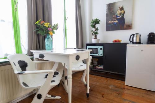 a white desk with two chairs and a vase with flowers at Tulip of Amsterdam in Amsterdam