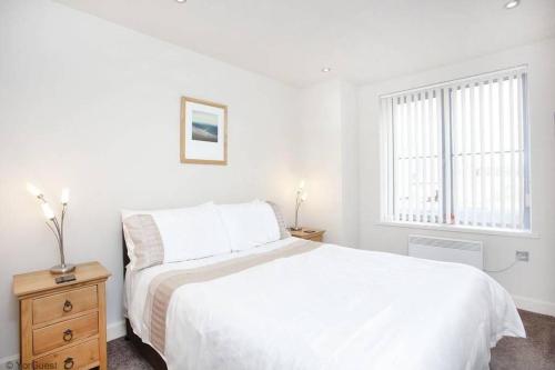a white bedroom with a white bed and a window at Apartment 12 Popeshead Court in York