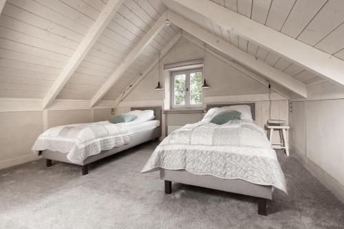 a attic bedroom with two beds and a window at Poduszka Apartamenty Kamienica in Pasłęk