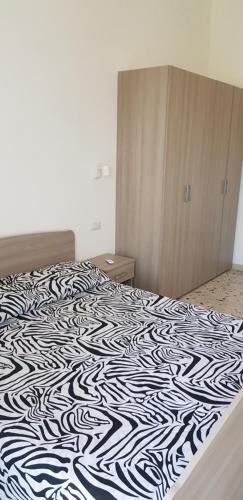 um quarto com uma cama com um cobertor preto e branco em LE ZAGARE abit SOLE a 5 minuti a piedi dal mare e dal centro em Formia