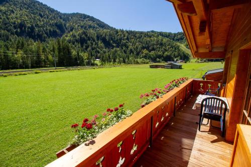 a porch of a house with flowers and a field at Landhaus Mair in Scharnitz
