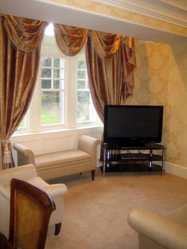 a living room with a flat screen tv and chairs at Mansion House Hotel in Elgin