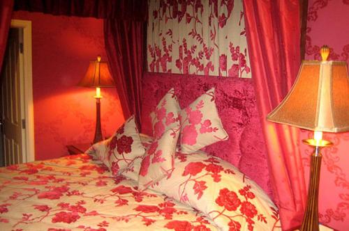 a bedroom with a bed with red walls and two lamps at Mansion House Hotel in Elgin