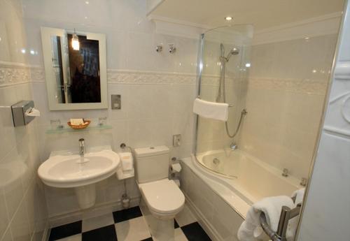 a bathroom with a toilet and a sink and a tub at Mansion House Hotel in Elgin