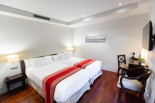 a bedroom with a large white bed and a chair at Hotel Rio Bidasoa in Hondarribia