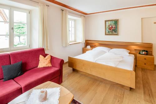 um quarto com uma cama grande e um sofá vermelho em Goldene Rose em Naturno