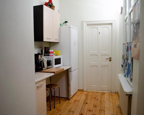 a small kitchen with a white refrigerator and a wooden floor at Red Nose Hostel with Self-Check In in Riga