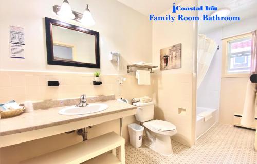 a bathroom with a sink and a toilet and a mirror at Coastal Inn Antigonish in Antigonish