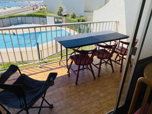 balcón con mesa y sillas junto a la piscina en Logement entier vue sur mer !, en Palavas-les-Flots