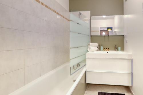 une salle de bain blanche avec un lavabo et un miroir dans l'établissement Apartment Virtuose - Disneyland Paris 5min - Train station 250m, à Montévrain