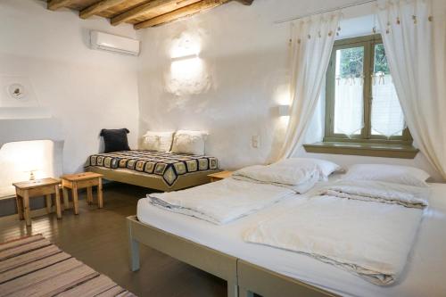 a bedroom with two beds and a window at Ghermaniko Guesthouse in Damouchari
